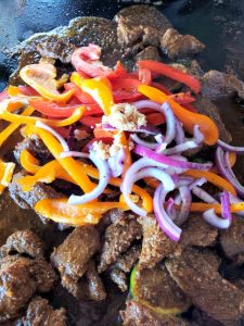 Blackstone steak fajitas cooking on blackstone griddle with vegetables