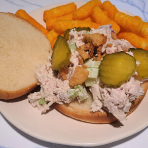 Smoked Turkey Salad on a bun on a plate served with cheese puffs