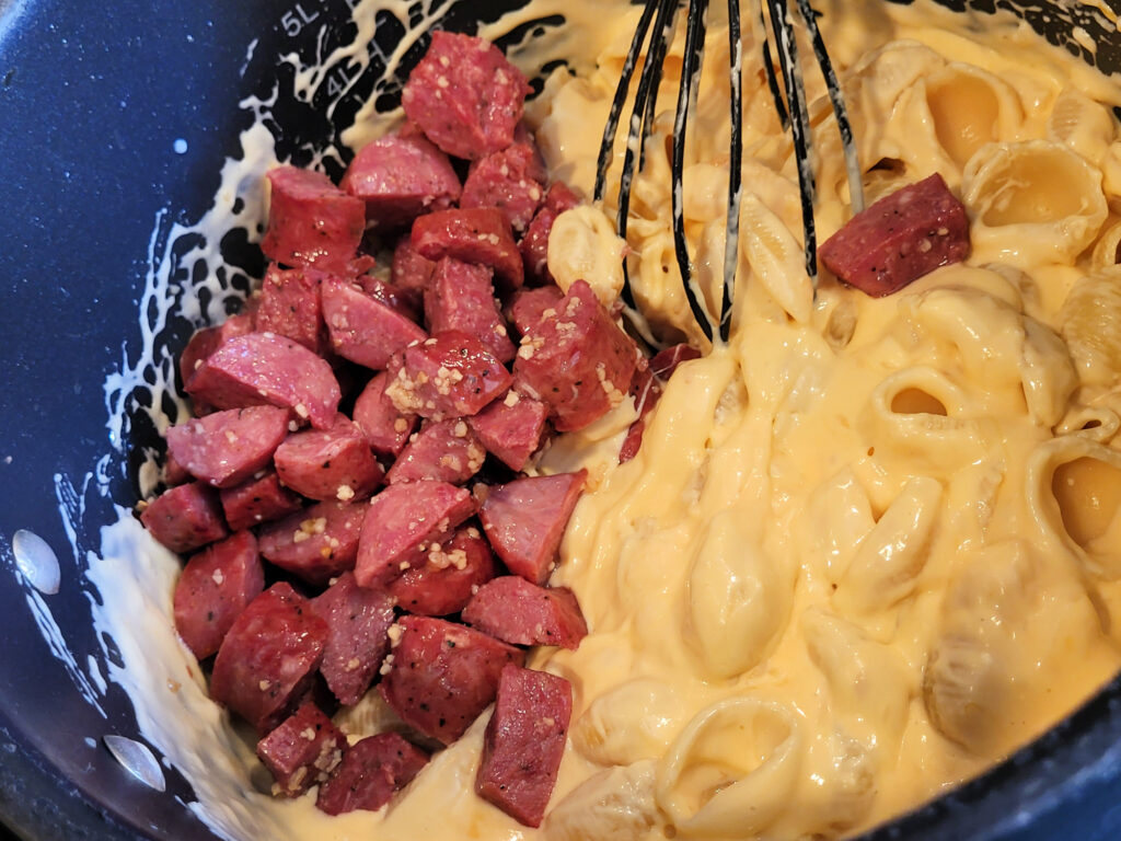 Sausage being mixed into mac and cheese