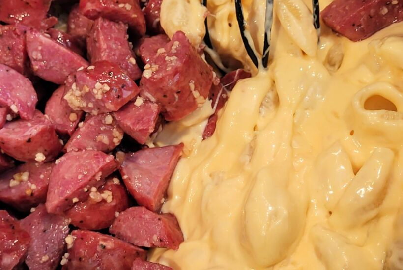 Macaroni and cheese next to cut beef sausage