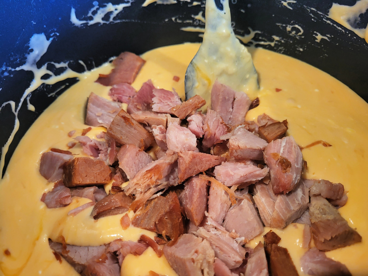 Shredded ham on top of melted cheese sauces for smoked ham mac and cheese