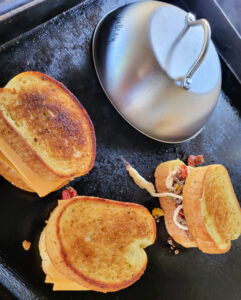 Cooked philly cheesesteak grilled with cheese dome on blackstone grilled