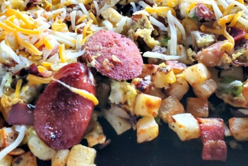 Blackstone Breakfast Hash Cooking on Blackstone Griddle Topped with cheese