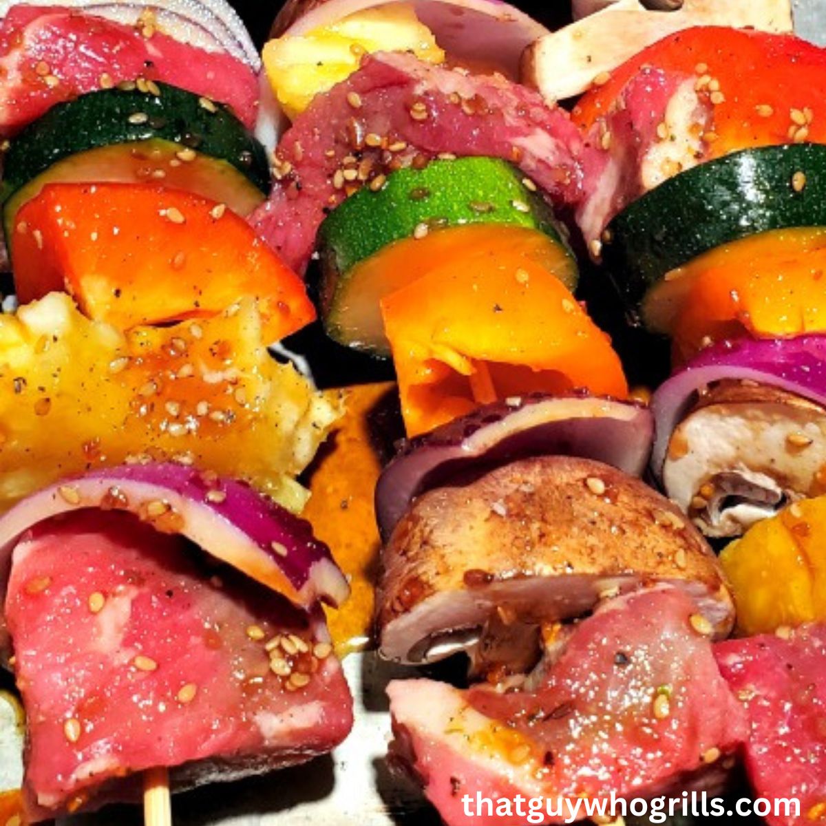 Kabobs with steak, red onions, mushrooms, bell peppers, and squash on them
