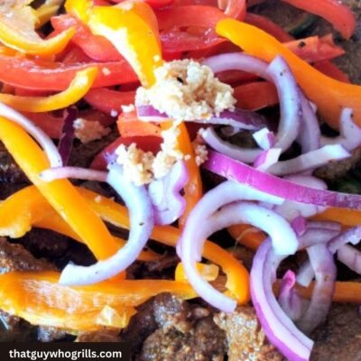 Steak fajitas cooking with peppers and red onion on blackstone griddle