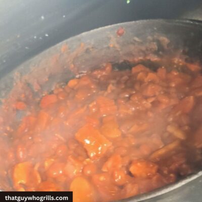 Smoked Loaded Baked Beans cooking in cast iron dutch oven in pellet grill