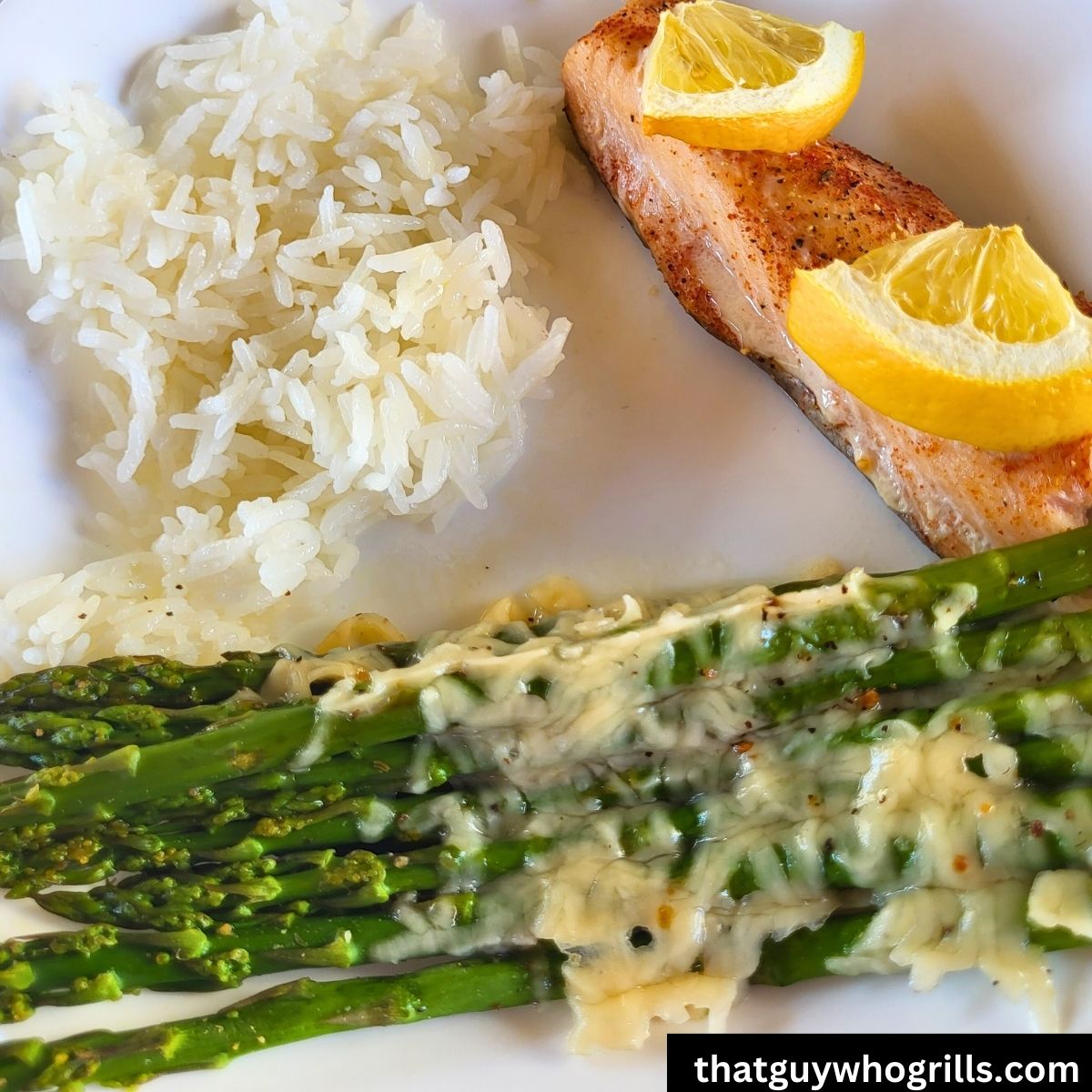 Grilled Salmon on a white plate with cheesy asparagus and white rice